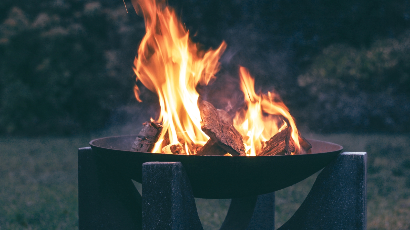 Fire pit lit at night in a small garden
